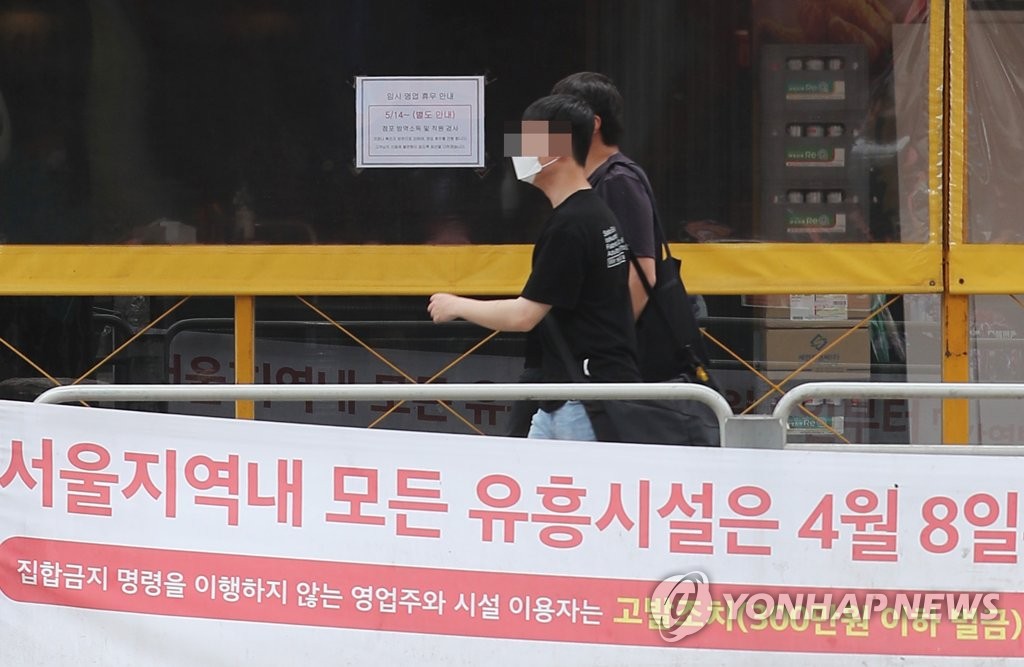 People pass by a bar, which has been closed due to the new coronavirus pandemic, in a university district in western Seoul on May 17, 2020. (Yonhap)