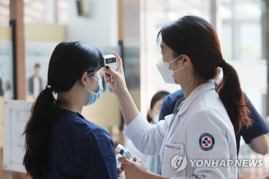 A medical worker checks visitors' temperatures ahead of a free music concert at the Seoul Medical Center in eastern Seoul on June 4, 2020. (Yonhap)