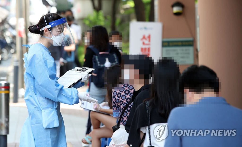 A health worker assists people waiting to be checked for the virus at a community health center in the southwestern Seoul ward of Gwanak on June 5, 2020. (Yonhap)