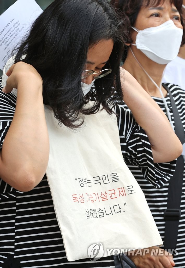 Members of an organization representing victims of a deadly humidifier sanitizer scandal hold a press conference in Seoul on July 31, 2020, demanding that a special counsel probe relevant government ministries and companies. One of the participants is seen holding an object with text that reads, "The government murdered citizens with a toxic humidifier sanitizer." (Yonhap)