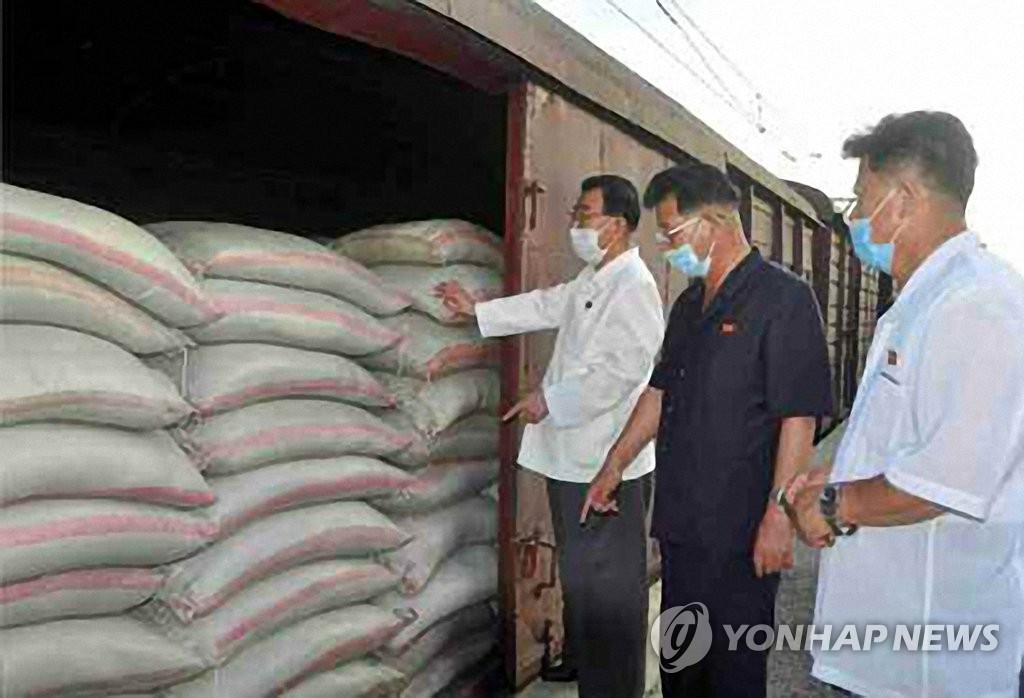 This photo captured from the Rodong Sinmun, the newspaper of North Korea's ruling Workers' Party, shows party officials inspecting rice bags that arrived at Kaesong station on Aug. 7, 2020. (PHOTO NOT FOR SALE) (Yonhap)
