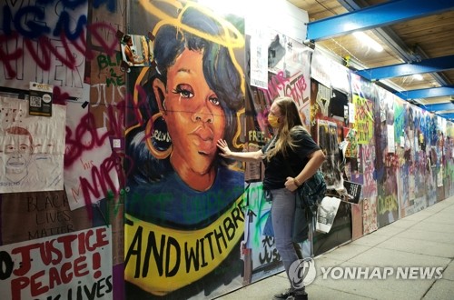 '경찰 총기 피격 사망' 테일러 얼굴 벽화 어루만지는 미 여성