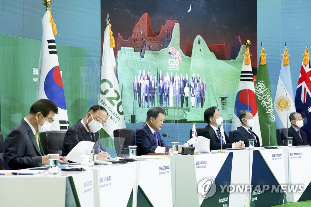 テレビ会議形式のＧ２０首脳会議に出席した韓国の文在寅（ムン・ジェイン）大統領（左から３人目）。背後には各国首脳が並んでいるように合成した写真がある＝２２日、ソウル（聯合ニュース）
