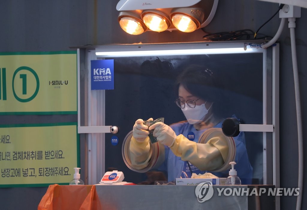 A medical worker at a temporary COVID-19 screening station warms up her hands on Dec. 24, 2020. (Yonhap)