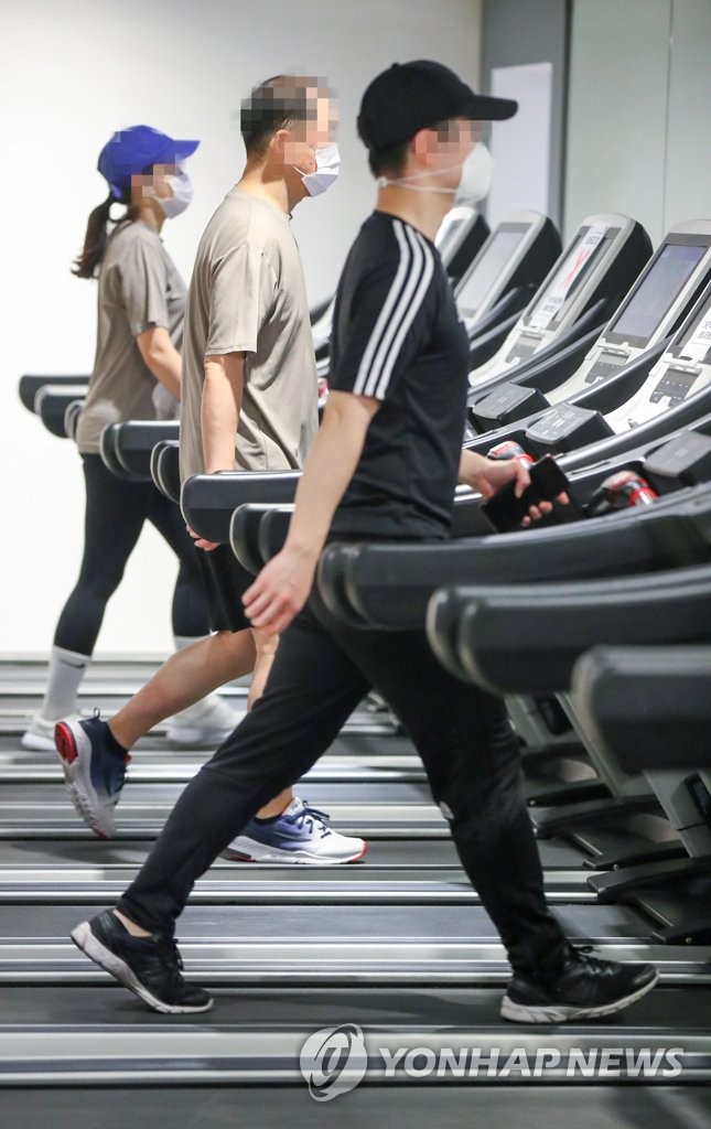 People walk on treadmills at a gym in Seoul on Jan. 18, 2021, as health authorities eased restrictions on cafes, gyms and other indoor facilities the same day amid signs of a letup in new coronavirus cases. (Yonhap)