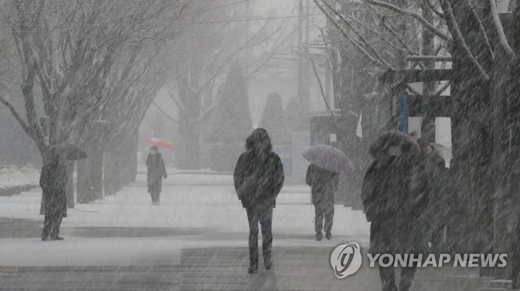 This file photo, taken Jan. 28, 2021, shows people walking in heavy snow in Seoul. (Yonhap)