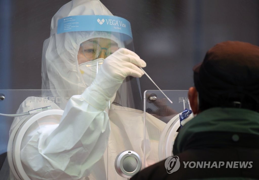 A health worker conducts a COVID-19 test on a citizen at a temporary testing site in a plaza in front of Seoul Station in central Seoul on Jan. 20, 2021. (Yonhap)