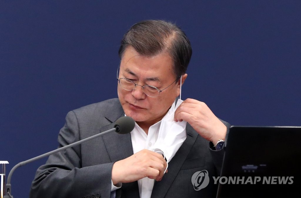President Moon Jae-in takes off a mask before making opening remarks during a meeting with senior secretaries at Cheong Wa Dae in Seoul on April 26, 2021. (Yonhap)