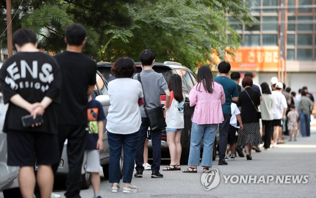 Des gens attendent avant de passer un test de dépistage du nouveau coronavirus (Covid-19) devant un centre provisoire à Chuncheon, à 85 kilomètres au nord-est de Séoul, le 22 juin 2021.