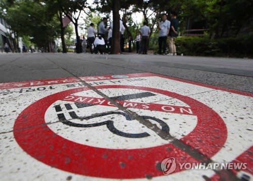서울 여의도의 한 흡연 부스 앞에서 직장인들이 담배를 피우는 모습 [연합뉴스 자료사진]