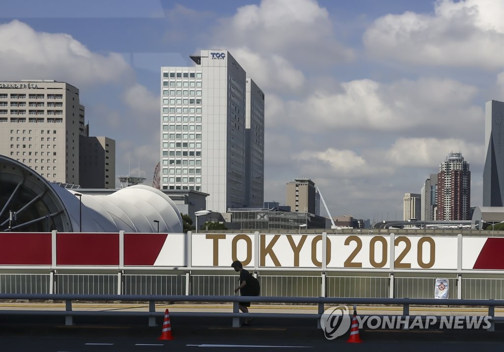 A pedestrian walks past a Tokyo 2020 banner in Tokyo on July 20, 2021. (Yonhap)