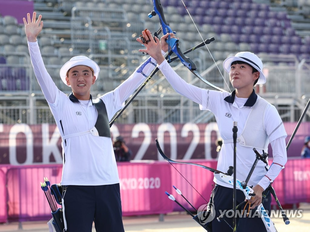 South Korean archers Kim Je-deok (L) and An San celebrate after clinching the gold medal in the mixed team event at the Tokyo Olympics at Yumenoshima Park Archery Field in Tokyo on July 24, 2021. (Yonhap)