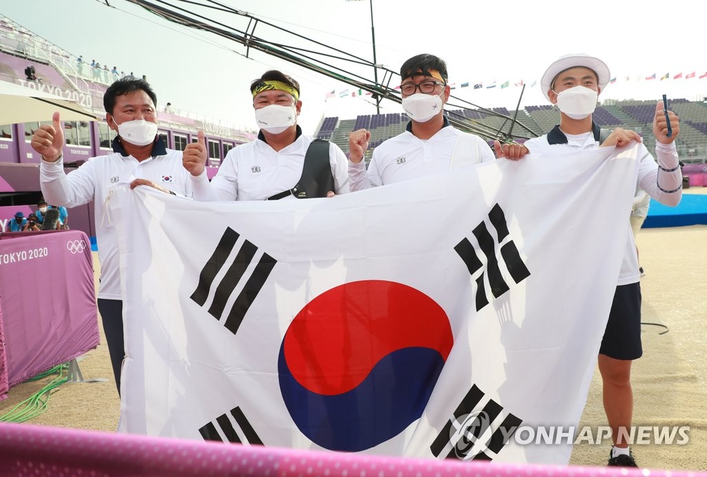 From left to right: South Korean archery head coach Hong Seung-jin, archers Oh Jin-hyek, Kim Woo-jin and Kim Je-deok pose with the national flag, Taegeukgi, after winning the men's team gold medal at the Tokyo Olympics at Yumenoshima Park Archery Field in Tokyo on July 26, 2021. (Yonhap)