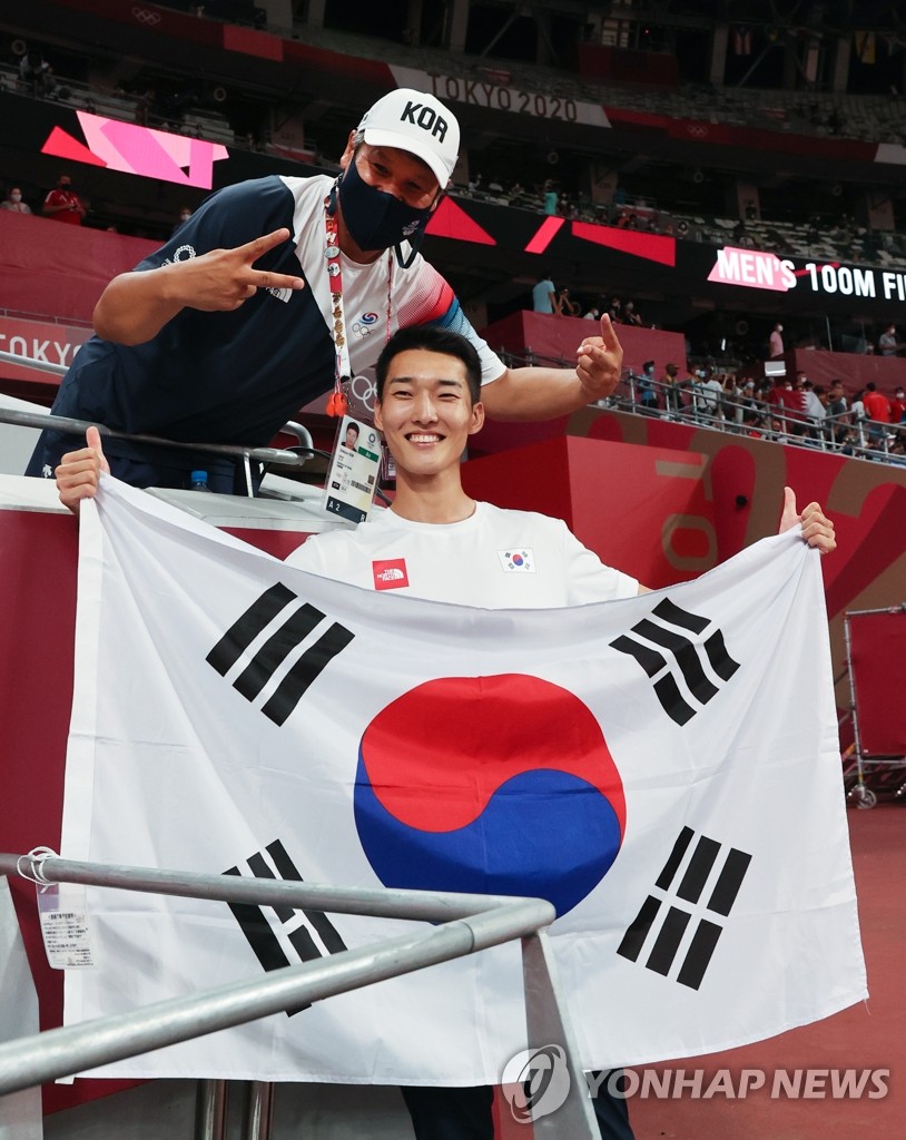 South Korean Woo Sang-hyeok (R) poses with the Korean national flag after the finals of men's high jump at the Tokyo Olympics at the Olympic Stadium in Tokyo on Aug. 1, 2021. (Yonhap)