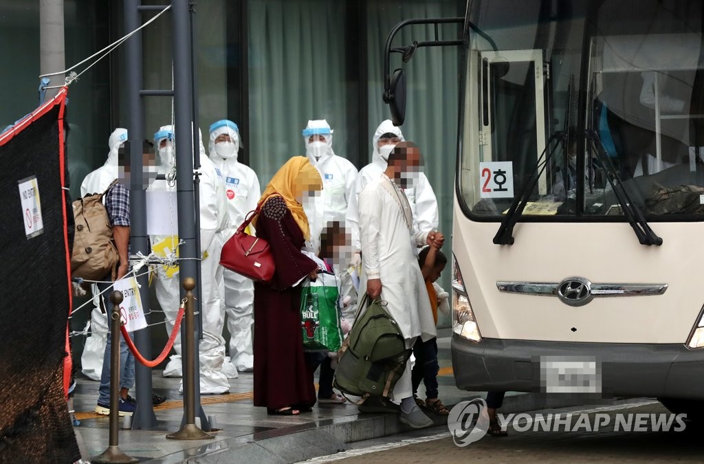 Afghan evacuees get on a bus in Gimpo, west of Seoul, on Aug. 27, 2021, to head for a state-run human resources development center in Jincheon, 91 kilometers southeast of Seoul. About 380 Afghans, who have worked for South Koreans in the war-ravaged nation, and their family members were airlifted to South Korea the previous day. (Yonhap)
