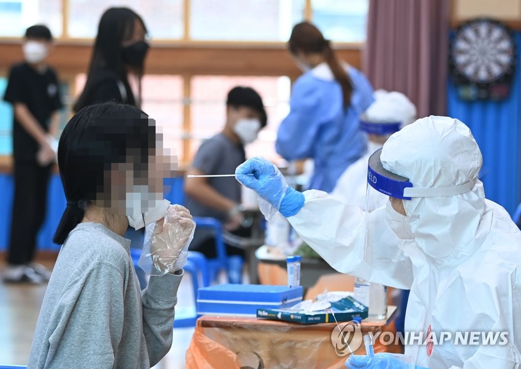 A medical worker collects specimen from a student in Gwangju, some 330 kilometers south of Seoul, after 13 tested positive for COVID-19. (Yonhap) 