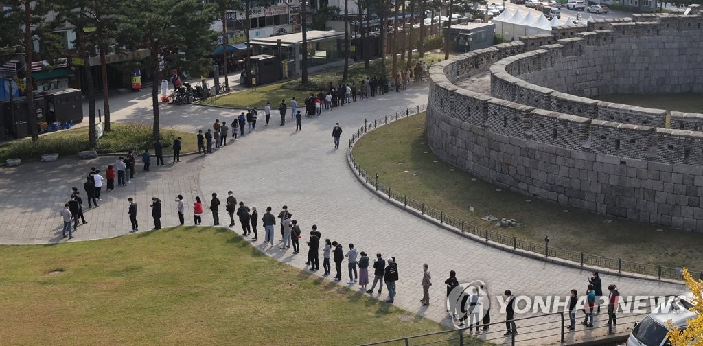 People line up in front of Dongdaemun Gate, designated as National Treasure No. 1, in Seoul's Jongno Ward on Oct. 22, 2021, to take coronavirus tests at a nearby screening center after the discovery that 152 people connected to a market in the ward have been infected with COVID-19 since Oct 6. (Yonhap)