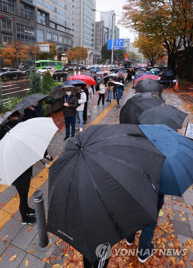 People holding umbrellas in the rain wait in line to take tests at a COVID-19 testing station in Seoul on Nov. 8, 2021, when the country reported 1,760 new cases. (Yonhap)
