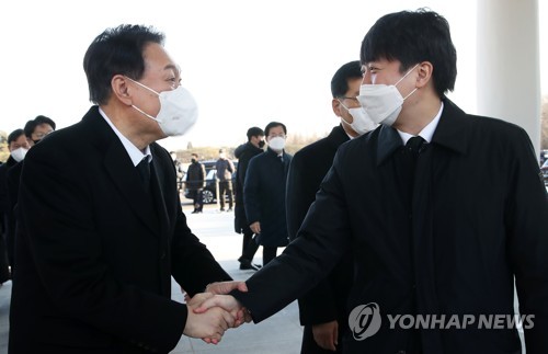 Yoon Suk-yeol (L), the presidential candidate of the main opposition People Power Party, shakes hands with Lee Jun-seok, the party's chairman, during their visit to the National Cemetery in Seoul on Jan. 1, 2022. They met for the first time since Lee quit Yoon's campaign on Dec. 21, 2021, following a row with senior officials close to Yoon. (Yonhap)