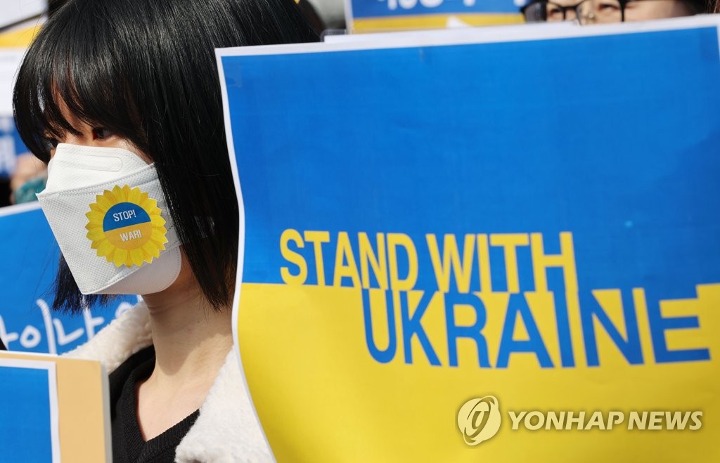A woman protesting Russia's war on Ukraine holds a sign in Seoul on March 8, 2022. (Yonhap)