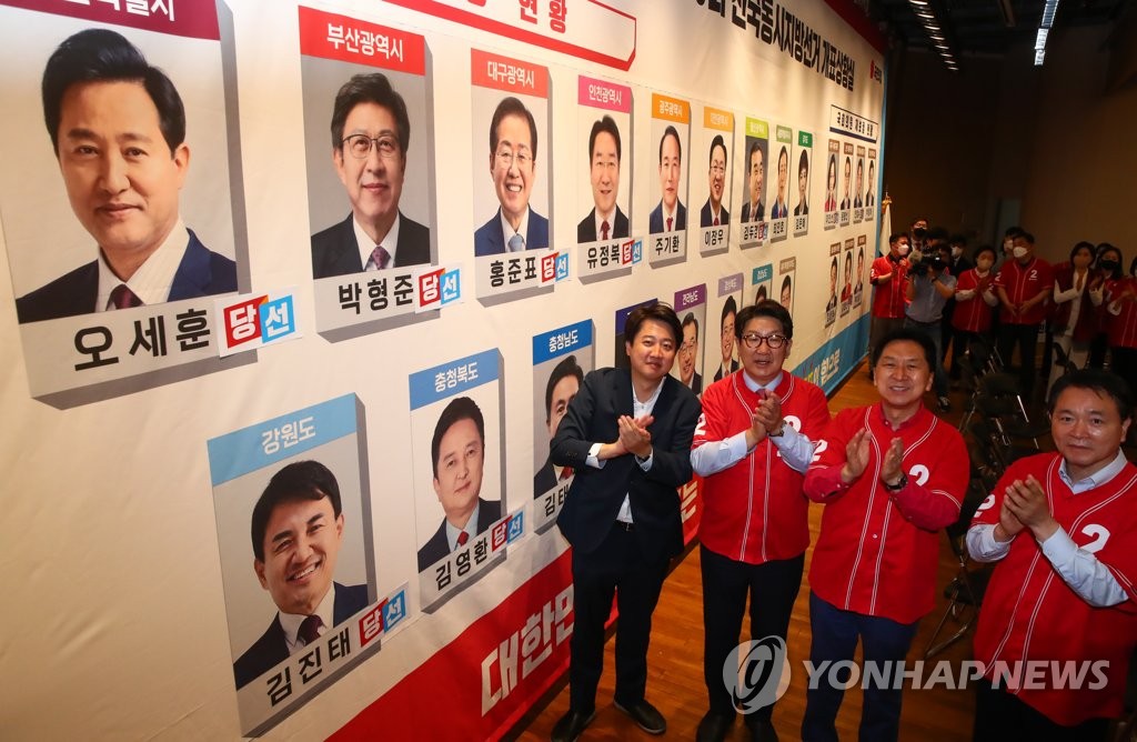 Des dirigeants du Parti du pouvoir du peuple (PPP) célèbrent leur victoire en apposant des autocollants sur les photos des candidats qui devraient remporter les élections locales à l'Assemblée nationale à Séoul, le jeudi 2 juin 2022. 