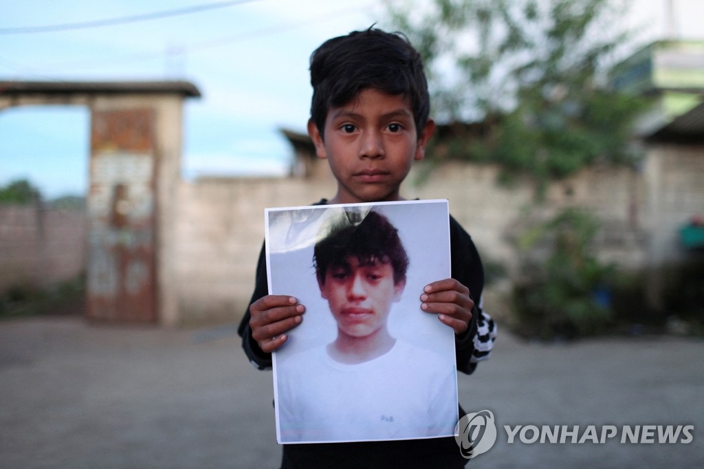 美 트레일러서 숨진 13세 소년 사진 들고 있는 과테말라 아이