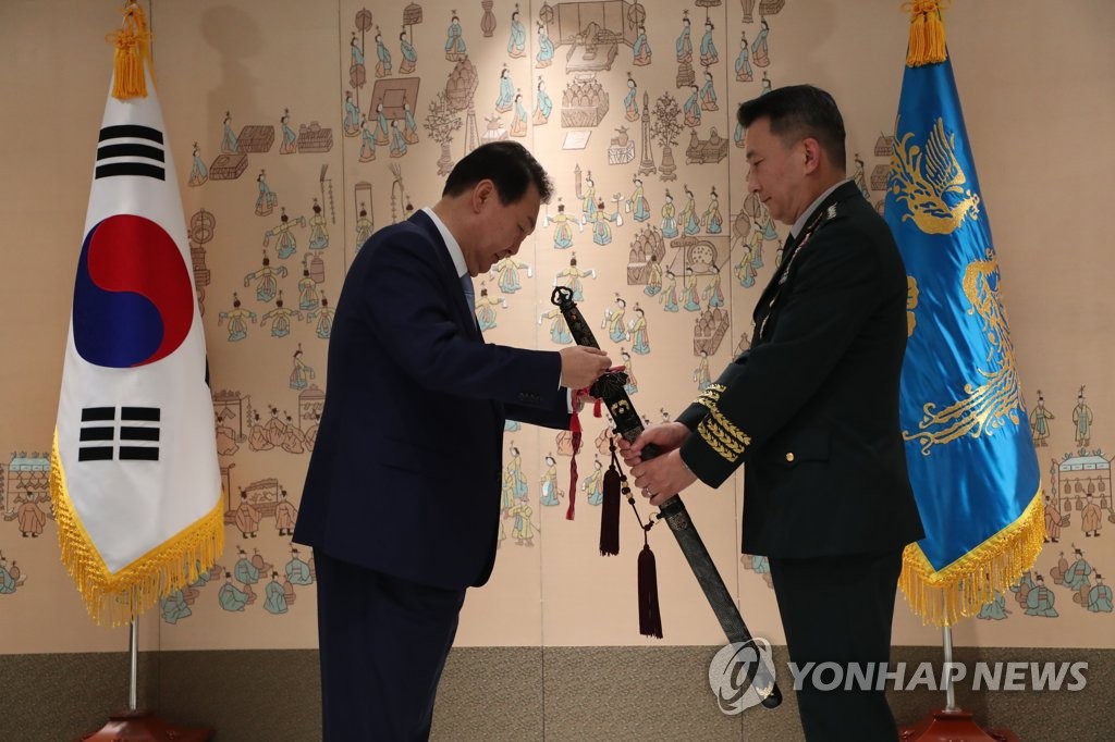 Le président Yoon Suk-yeol (à g.), serre la main du nouveau chef du Comité des chefs d'état-major interarmées (JCS), le général de l'armée de terre Kim Seung-kyum, lors d'une cérémonie de remise de l'épée coréenne traditionnelle «Sam Jeong Geom», ou l'épée des trois esprits, pour célébrer son investiture, au bureau présidentiel à Séoul le mardi 5 juillet 2022. (Pool photo)