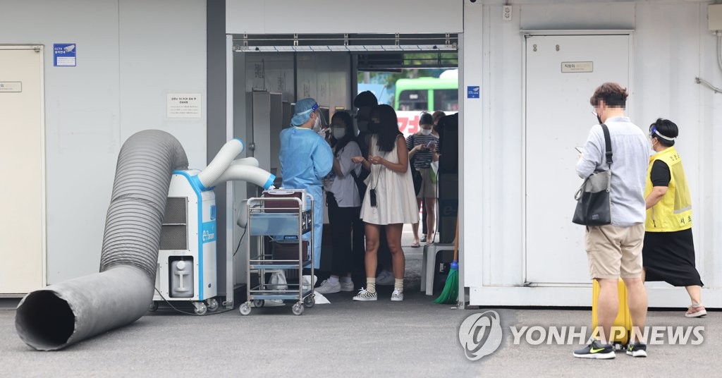 Los ciudadanos esperan en fila para ser examinados del coronavirus, el 27 de julio de 2022, en una clínica provisional en una terminal de autobuses, en el sur de Seúl.