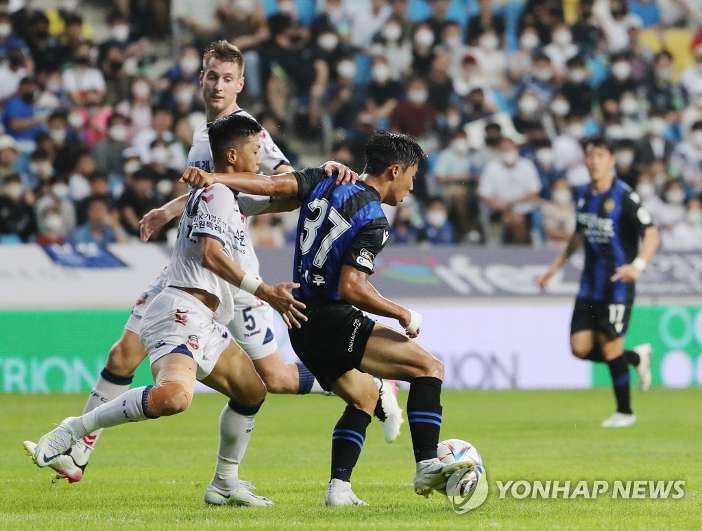 Shin Se-gye of Suwon FC (L) and Hong Si-hoo of Incheon United battle for the ball during their clubs' K League 1 match at Incheon Football Stadium in Incheon, 30 kilometers west of Seoul, on Aug. 3, 2022. (Yonhap)