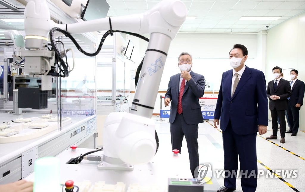 President Yoon Suk-yeol (R) watches a robot demonstration at the office of Ajinextek Co. in Daegu, 237 kilometers southeast of Seoul, on Aug. 26, 2022. (Yonhap)