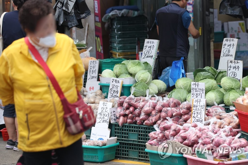 A woman walks by vegetables on display at a traditional market in Seoul on Aug. 29, 2022. (Yonhap)