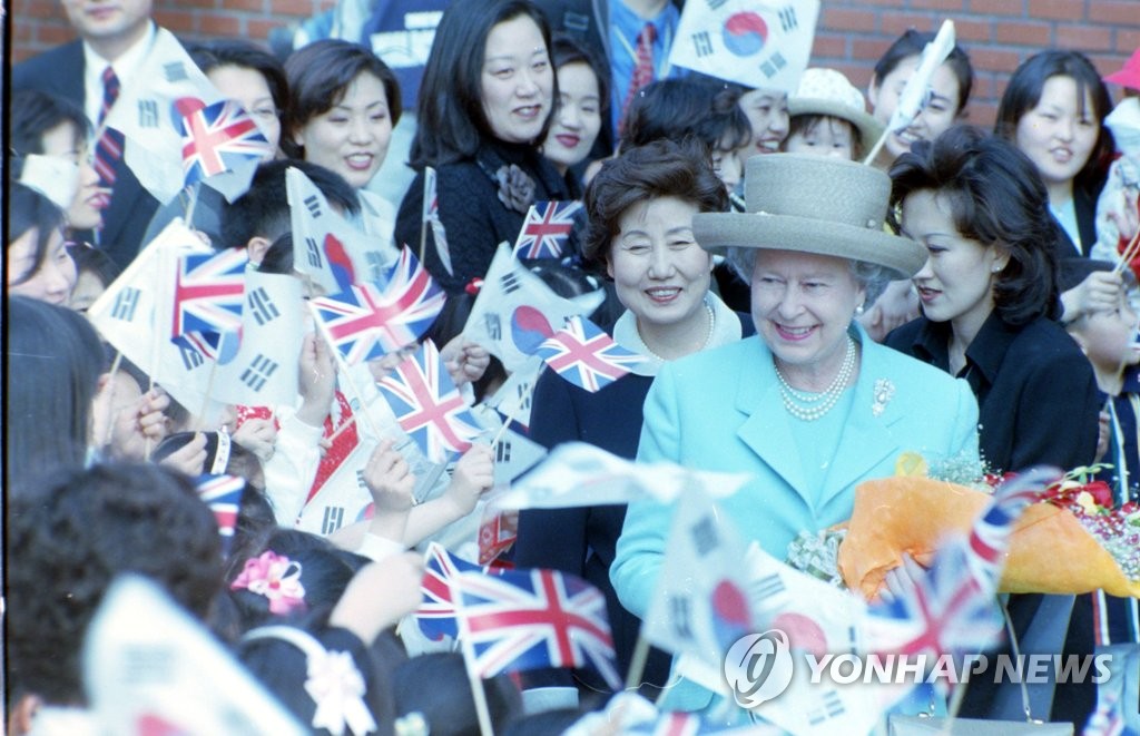 This 1999 file photo shows Queen Elizabeth II (R) being greeted by students at Midong Elementary School in Seoul during her visit to South Korea. (Yonhap)