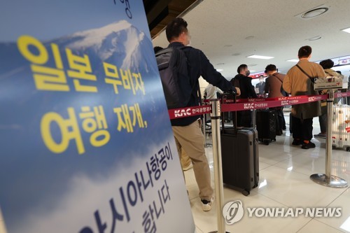 金浦国際空港のチェックインカウンターで順番を待つ羽田線の乗客＝１１日、ソウル（聯合ニュース）