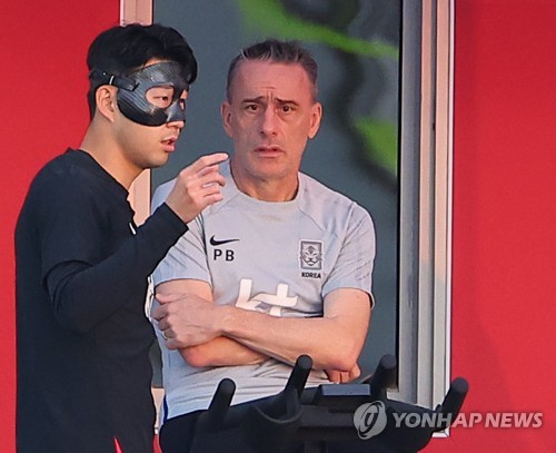 South Korean captain Son Heung-min (L) and head coach Paulo Bento speak with each other before a training session at Al Egla Training Site in Doha on Nov. 21, 2022. (Yonhap)