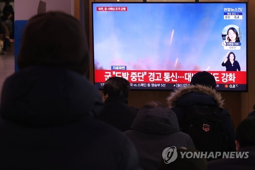 People watch a report at Seoul Station in Seoul on Dec. 5, 2022, on North Korea's artillery firings. (Yonhap)