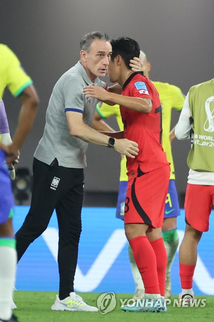 South Korea's head coach Paulo Bento (L) embraces midfielder Lee Kang-in following their 4-1 loss to Brazil in the round of 16 at the FIFA World Cup at Stadium 974 in Doha on Dec. 5, 2022. (Yonhap)