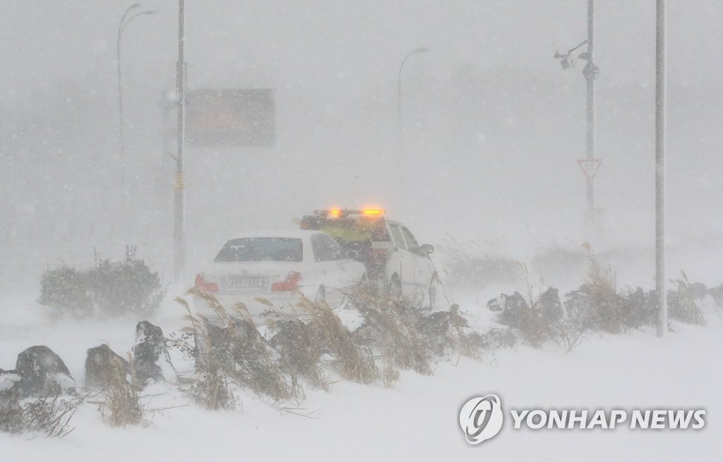 A vehicle is being towed away amid a blizzard in Jeju, Jeju Island, on Dec. 18, 2022. (Yonhap)