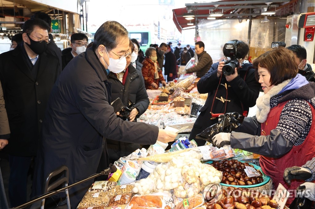 Le Premier ministre Han Duck-soo achète des produits alimentaires au marché traditionnel Gyeongdong à Séoul le mercredi 18 janvier 2023, à l'approche du Nouvel An lunaire. 