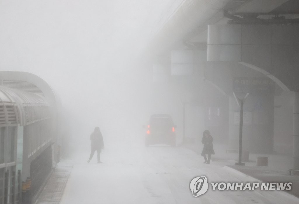 People cross the street amid a blizzard in the city of Jeju on South Korea's largest island of the same name on Jan 24, 2023. (Yonhap)