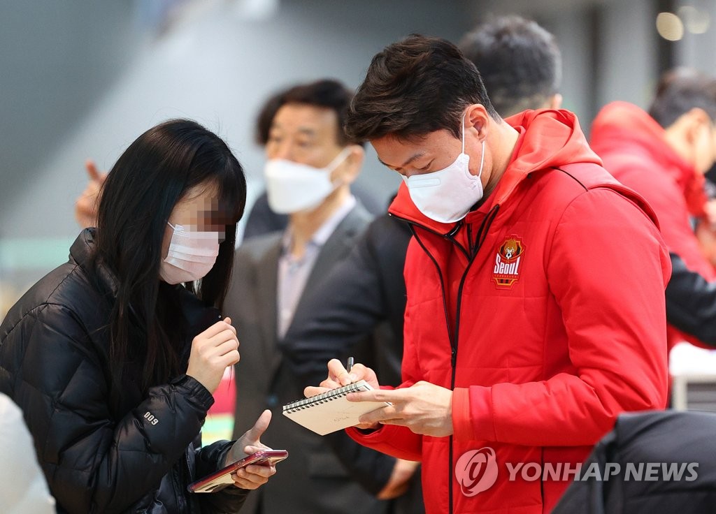FC Seoul forward Hwang Ui-jo (R) signs an autograph for a fan at Incheon International Airport, west of Seoul, before departing for Kagoshima, Japan, for training camp on Feb. 6, 2023. (Yonhap)