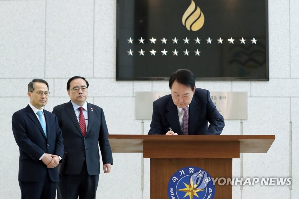 President Yoon Suk Yeol (R) signs a guest book during a visit to the National Intelligence Service headquarters in Seoul on Feb. 24, 2023, in this photo provided by the presidential office. (PHOTO NOT FOR SALE) (Yonhap)