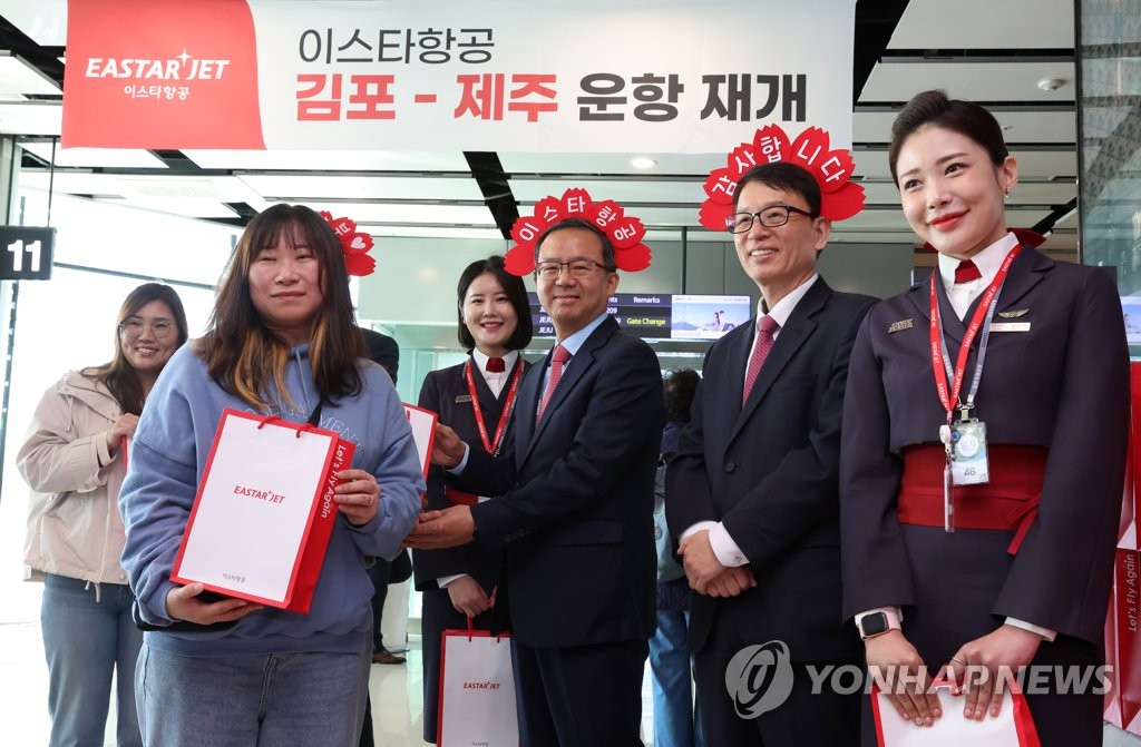 Eastar Jet CEO Cho Joong-seok (4th from L) and company officials pose for a photo with a passenger (2nd L) who won a promotional event celebrating the budget carrier's flight resumption after three years at the domestic terminal of Gimpo International Airport on March 26, 2023. (Pool photo) (Yonhap) 