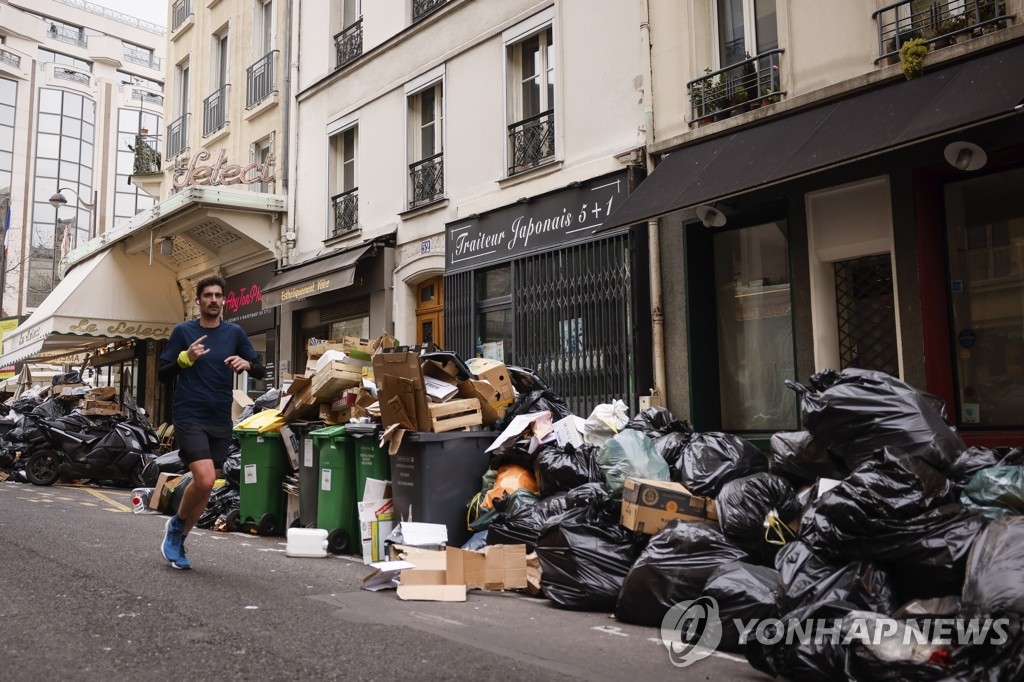 쓰레기 더미 쌓인 파리 거리서 조깅하는 시민