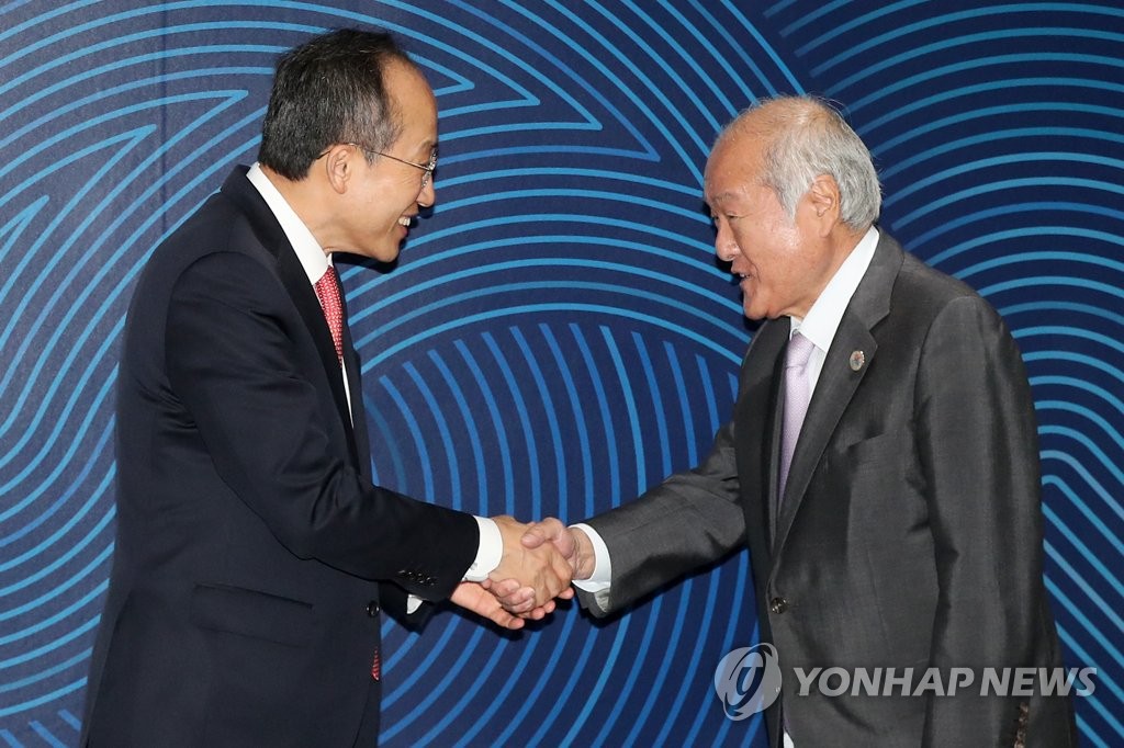 Finance Minister Choo Kyung-ho (L) shakes hands with his Japanese counterpart, Shunichi Suzuki, on the sidelines of the 56th Annual Meeting of the Board of Governors of the Asian Development Bank in Incheon, 36 kilometers west of Seoul. (Yonhap)