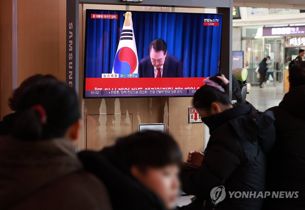 People watch news of President Yoon Suk Yeol's public address at Seoul Station in the capital city on Dec. 7, 2024. (Yonhap)