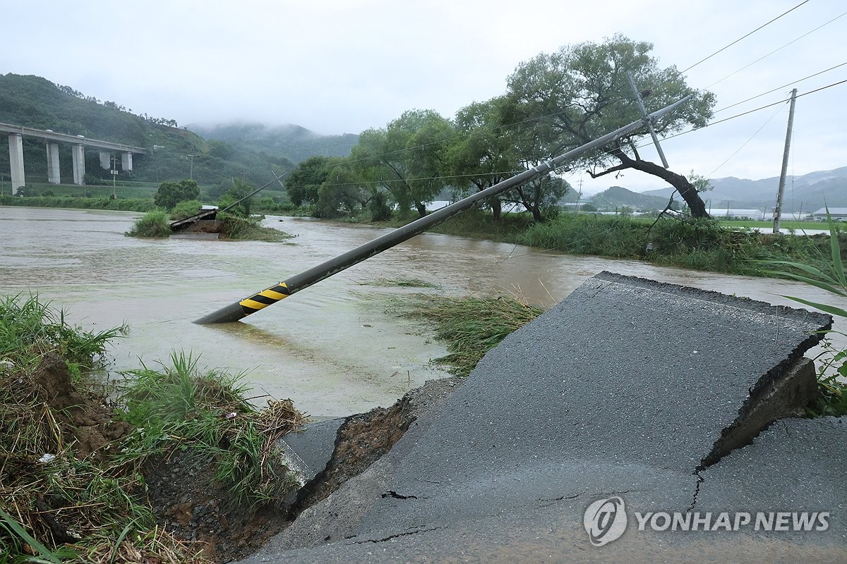 Varios postes del tendido eléctrico permanecen parcialmente caídos en una carretera colapsada por las fuertes lluvias, el 17 de julio de 2025, en Gongju, en la provincia de Chungcheong del Sur, en el centro del país.